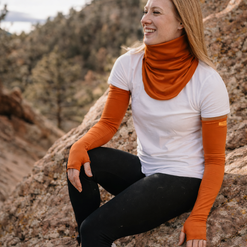 woman sitting on a rock wearing eclipse gaiter and sun sleeves