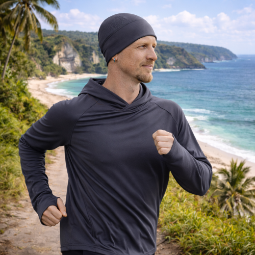 man running near beach wearing eclipse beanie and hoodie in graphite