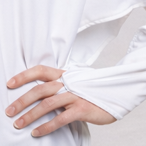 Woman wearing a white eclipse Equinox cover-up and black pants on a beach with palm trees in the background