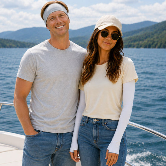 Man and woman standing on a boat with a scenic background wearing eclipse headband and sun sleeves
