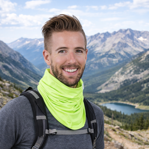 man with backpack and neon neck gaiter standing in front of mountains