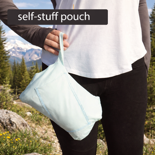 Person holding a self-stuff pouch holding the eclipse Equinox Reversible cover-up with mountains and trees in the background