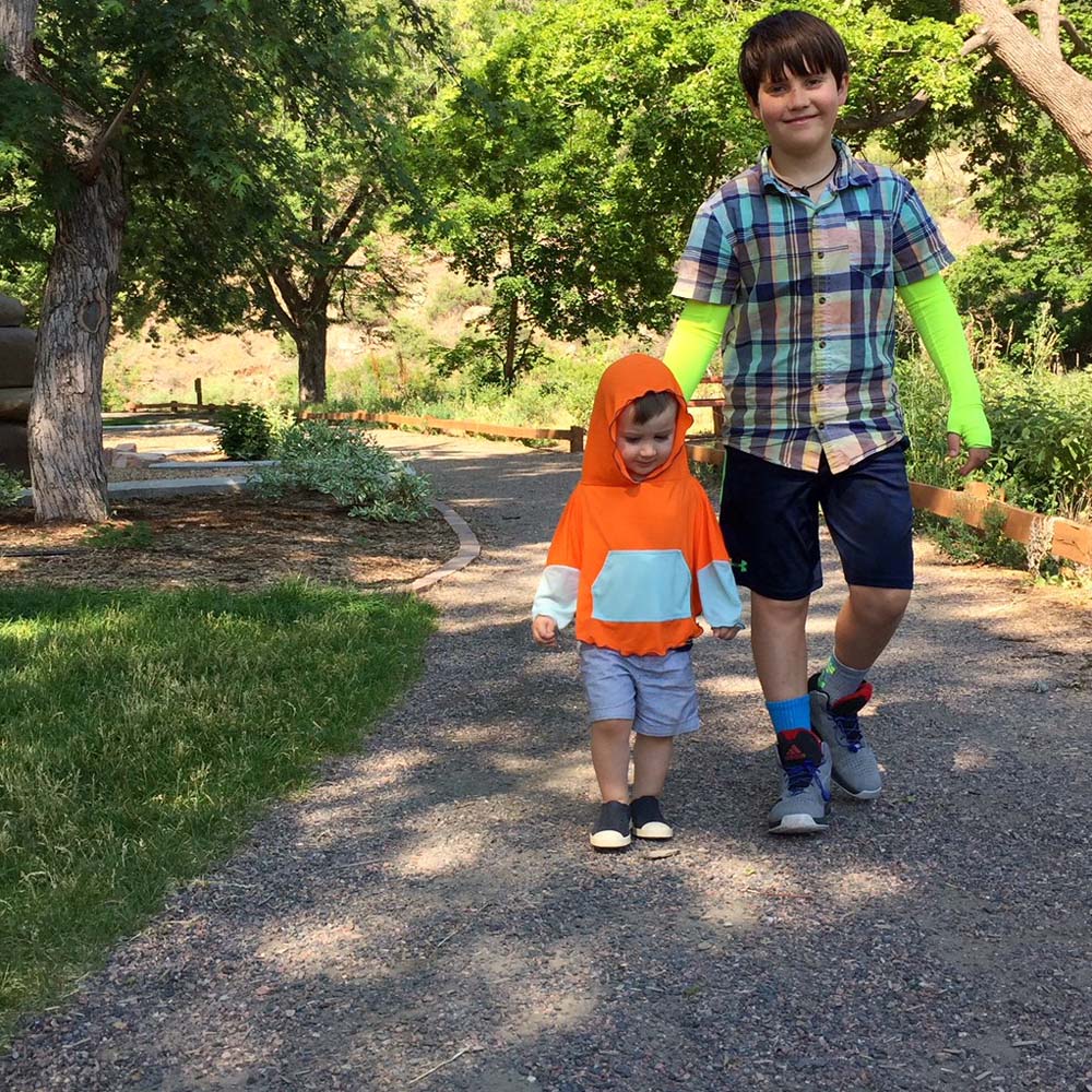 Boy wearing eclipse sun sleeves neon and child wearing sun poncho orange